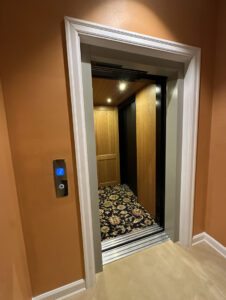 Garaventa Lift home elevator at second-floor landing in Iowa City, IA with open doors and wood interior cab.