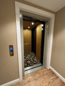 Garaventa Lift home elevator in Iowa City, IA shown with open doorway, wood interior cab, and hallway view