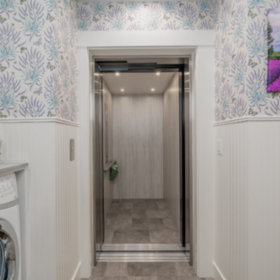 Closed stainless steel home elevator doors beside blue patterned wallpaper in an Edmonds, WA home